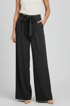 Model in palazzo trousers, relaxed seated pose