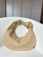 Woman holding woven bag at waist, front view