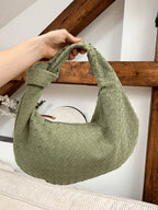 Woven shoulder bag worn by model, walking pose
