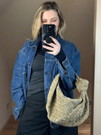 Woven shoulder bag worn on model against neutral background