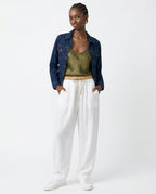Model seated wearing peach linen tapered trousers, showing comfort fit