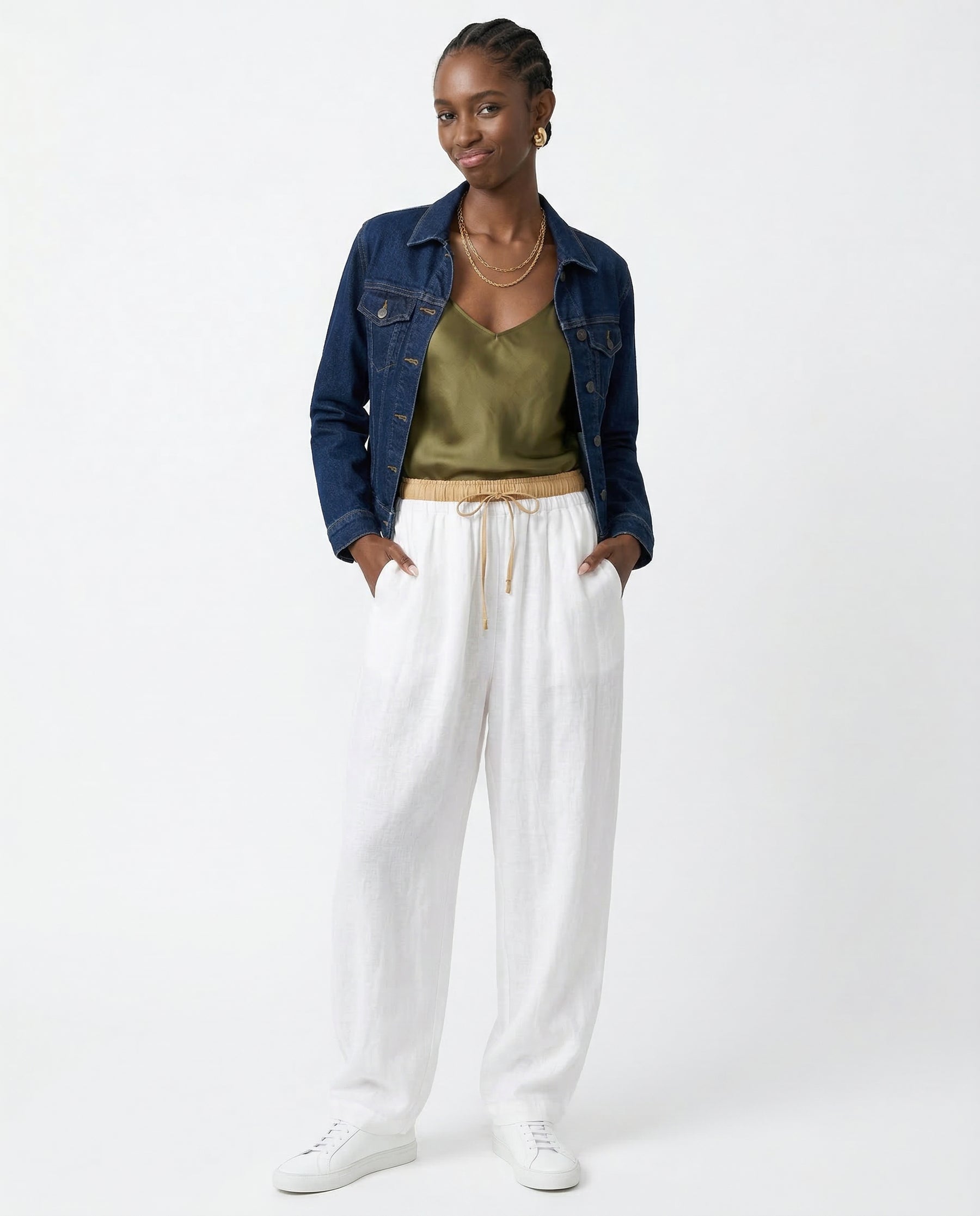 Model seated wearing peach linen tapered trousers, showing comfort fit