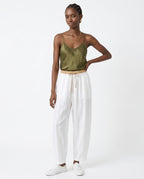 Waistband detail with sage green drawstring on peach linen trousers