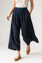 Three-quarter angle view of model in peach linen drawstring trousers