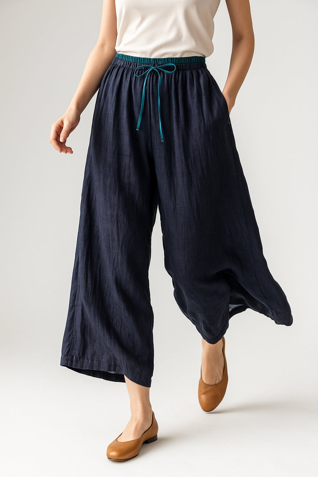 Three-quarter angle view of model in peach linen drawstring trousers
