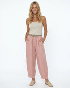 Model wearing peach linen trousers, standing pose showing drape and fit