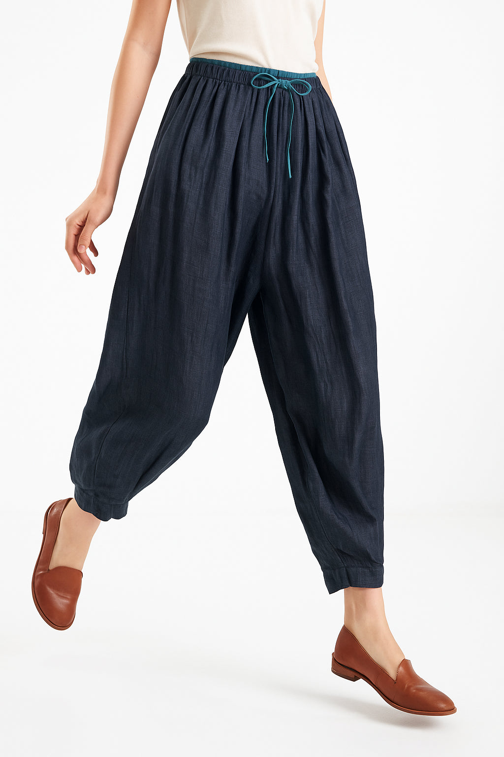 Flat lay detail showing drape and fabric of peach linen tapered trousers