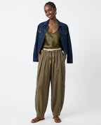 Model from behind in peach linen tapered trousers, showing back seam