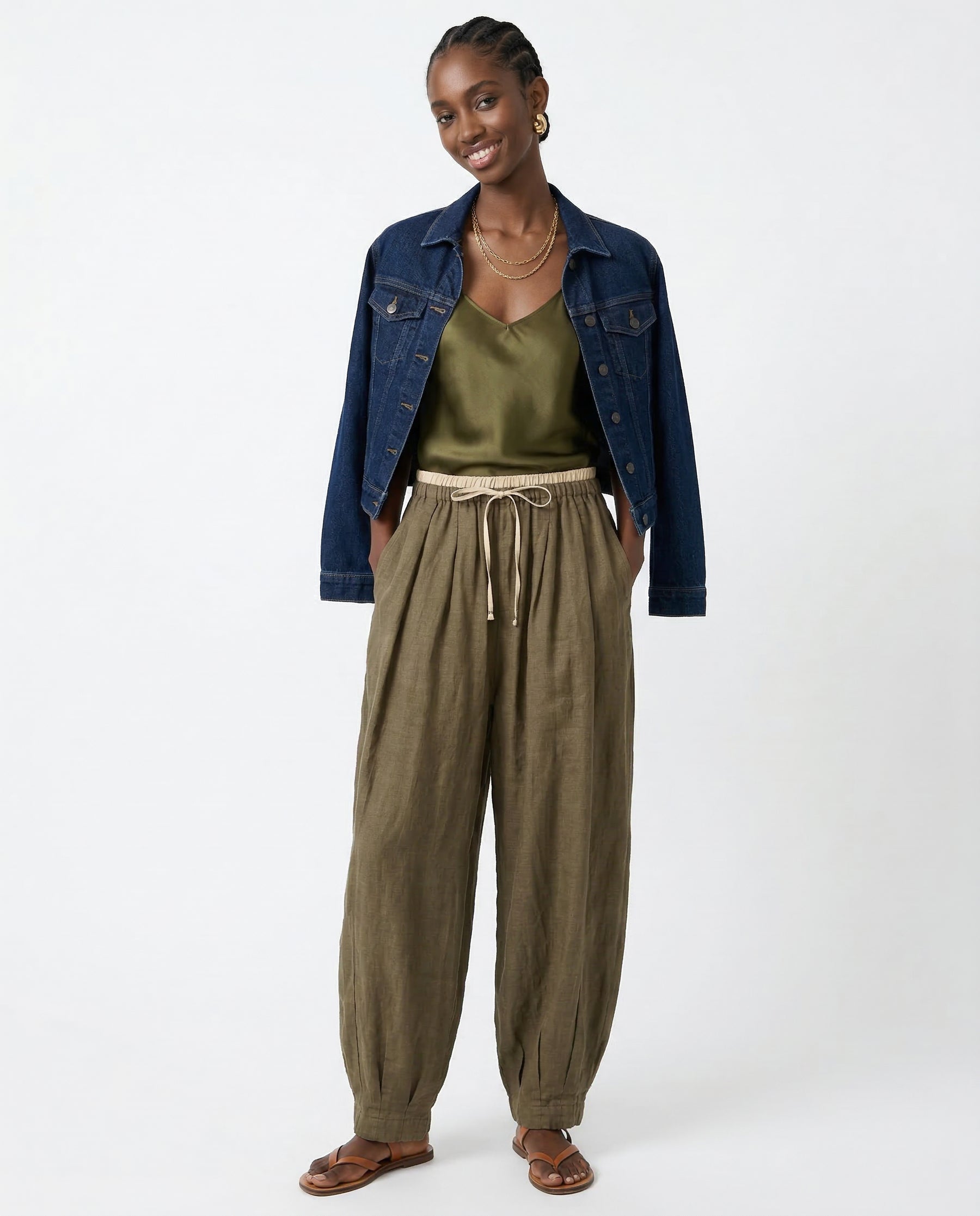 Model from behind in peach linen tapered trousers, showing back seam