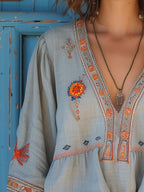 Close-up detail of coral and blue floral embroidery on blouse bodice