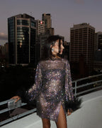 Model in sequin dress showing movement and feather cuff styling