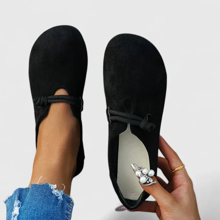 Woman wearing beige loafers whilst standing, showing full shoe profile