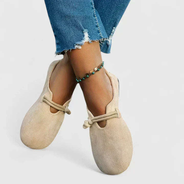 Woman's feet in beige loafers, seated pose showing shoe construction