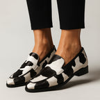 Woman wearing cow print loafers with pointed toe, styled for work