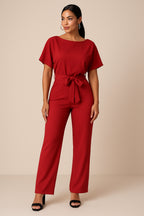 Model in jumpsuit standing with hand on hip, side profile