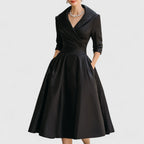 Woman wearing black faux leather midi dress with v-neck and 3/4 sleeves, front view