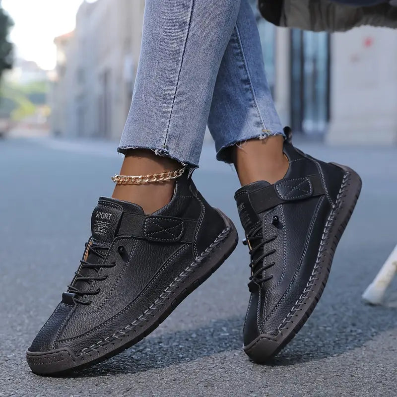 Black leather lace up trainer shown from the side on white background