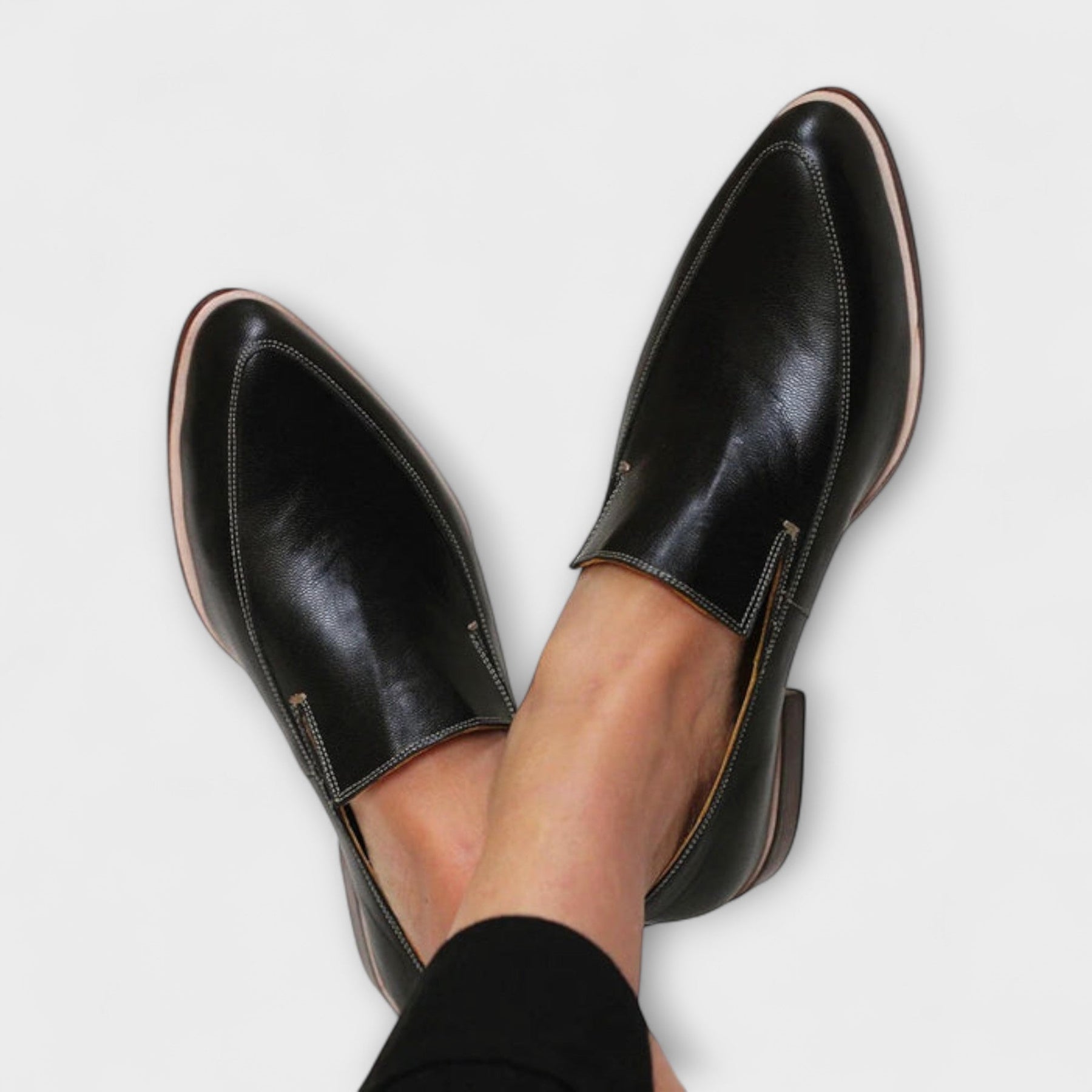 Black leather pointed toe loafers shown on a white background, side view