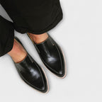 Woman wearing black leather loafers, standing pose showing front and side silhouette