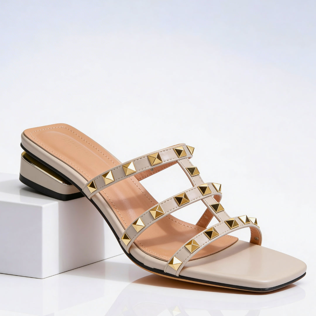 Woman wearing studded mules with cage strap detail, side profile shot