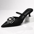 Black leather pointed toe kitten heel mule with white pearl flower embellishment, front view