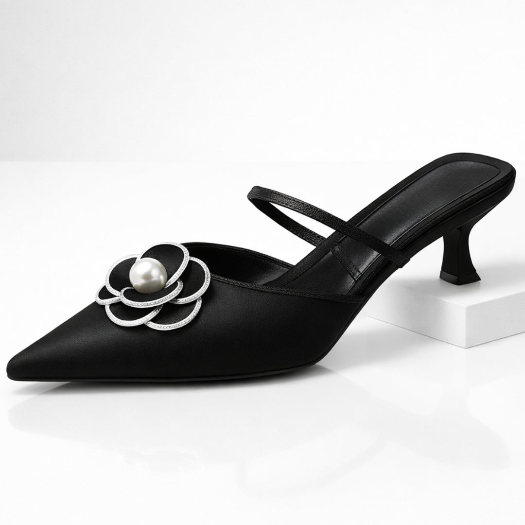 Close-up of white pearl-centred flower detail on black leather mule