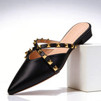 Women's pointed toe studded leather mules with gold pyramid stud detail on crossover straps