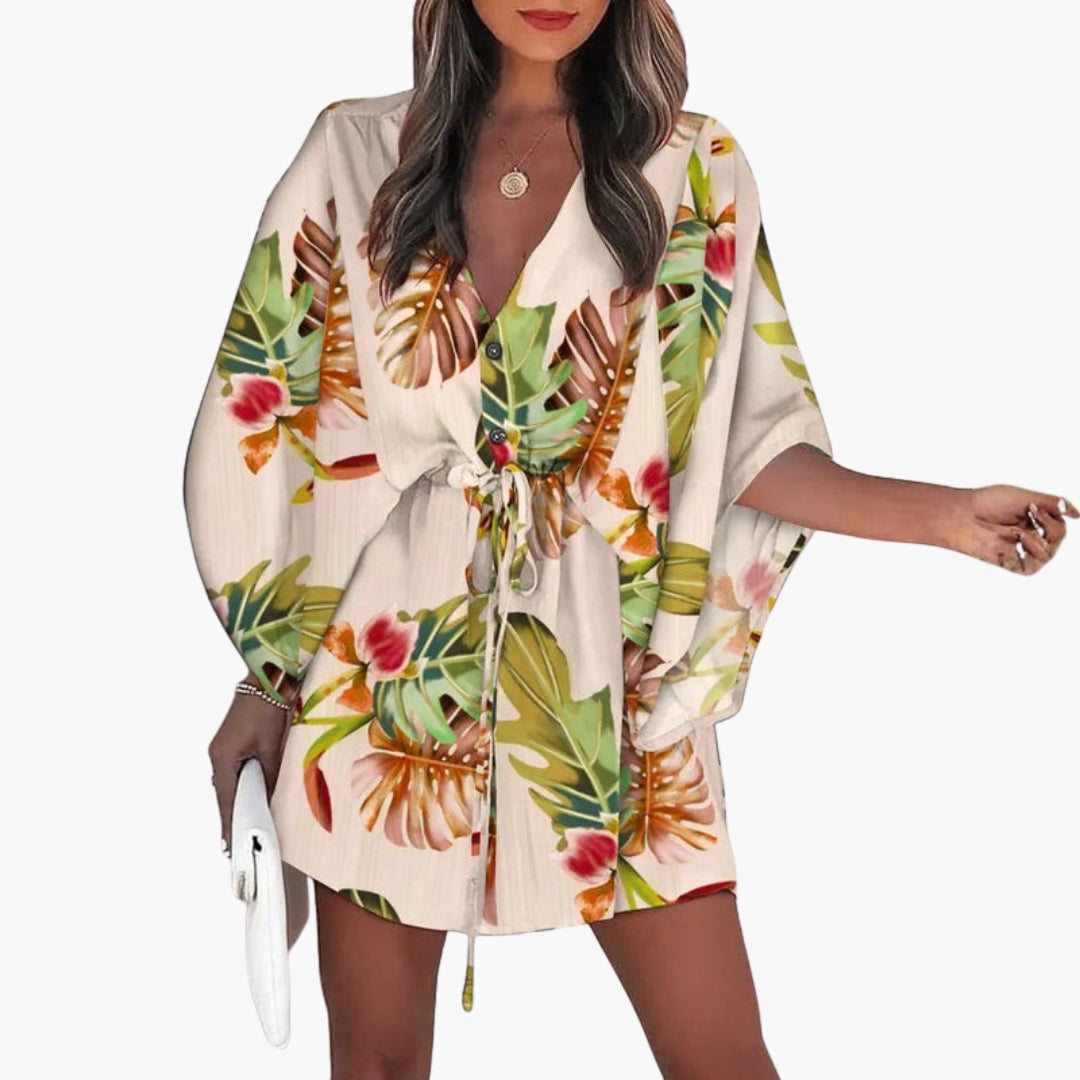 Side angle of tropical leaf dress highlighting adjustable tie waist and mini length