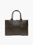 Woven tote bag worn over shoulder, styled for everyday wear