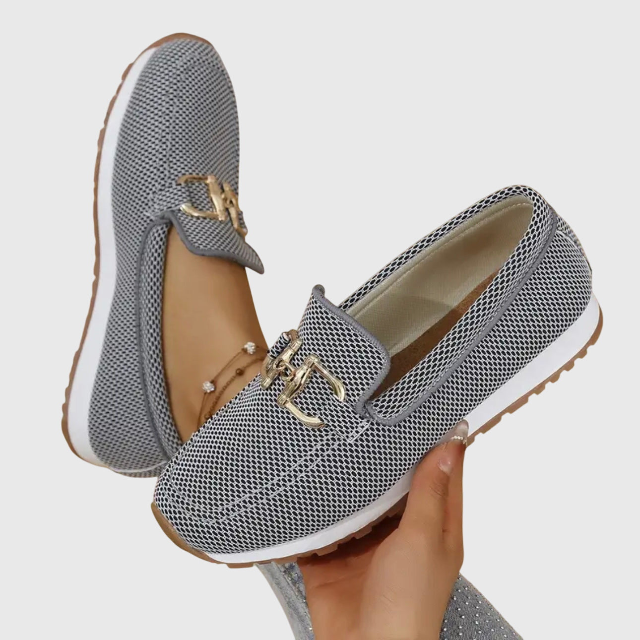 Woman seated wearing denim loafers, leg extended detail shot