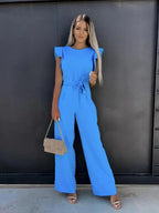 Model wearing blue jumpsuit, full length pose showing wide leg silhouette