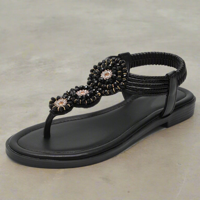 Model wearing pair of embellished sandals, walking shot on pavement
