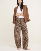 Leopard print wide leg jeans worn with white trainers, standing pose