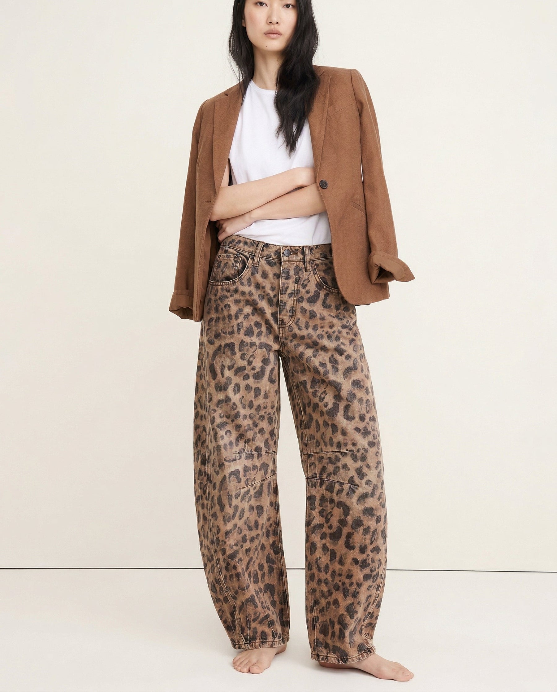 Leopard print wide leg jeans worn with white trainers, standing pose