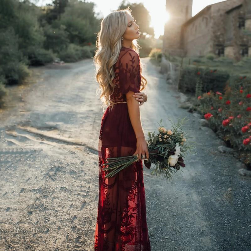 Model wearing burgundy lace maxi dress, side profile stance