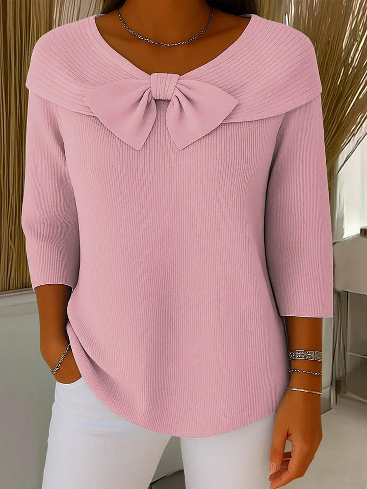 Close-up detail of ribbed knit texture and oversized bow neckline