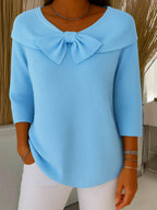 Model wearing burgundy bow collar top, posed from the side