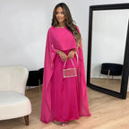 Model wearing cape maxi dress, front-facing pose with draped sleeves