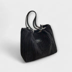 Woman holding bag with fabric shoulder strap, angled view