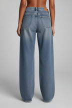 Woman wearing light blue wide leg jeans, back view