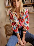 Model wearing floral blouse front view, showcasing red, pink, blue and green print
