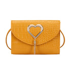 Mustard yellow croc embossed crossbody bag with silver heart clasp, front view