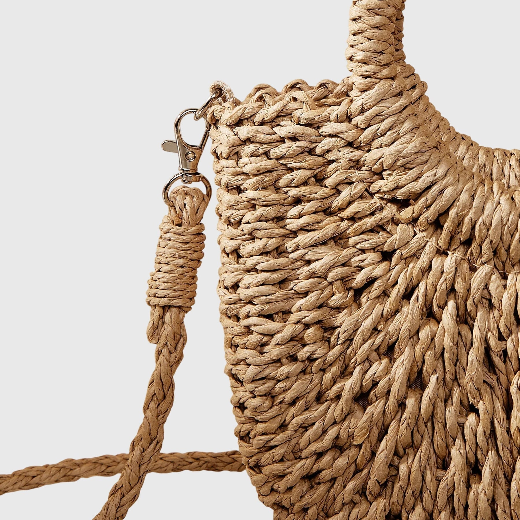 Circular woven handle detail on natural straw bag