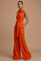Side profile of orange jumpsuit showing tie belt detail and flowing trousers