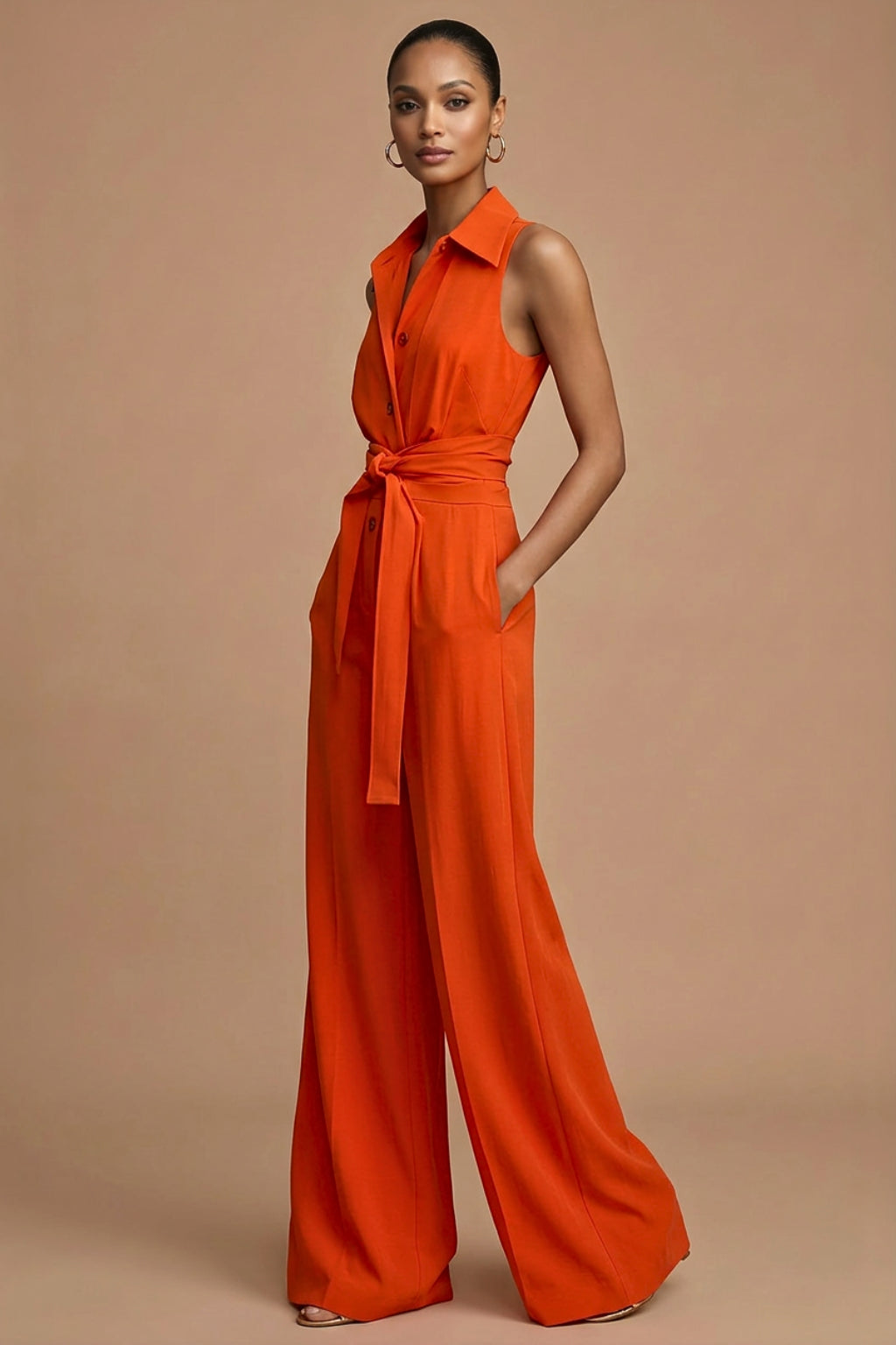 Side profile of orange jumpsuit showing tie belt detail and flowing trousers