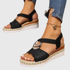 Woman's feet in espadrille wedge sandals on sandy surface
