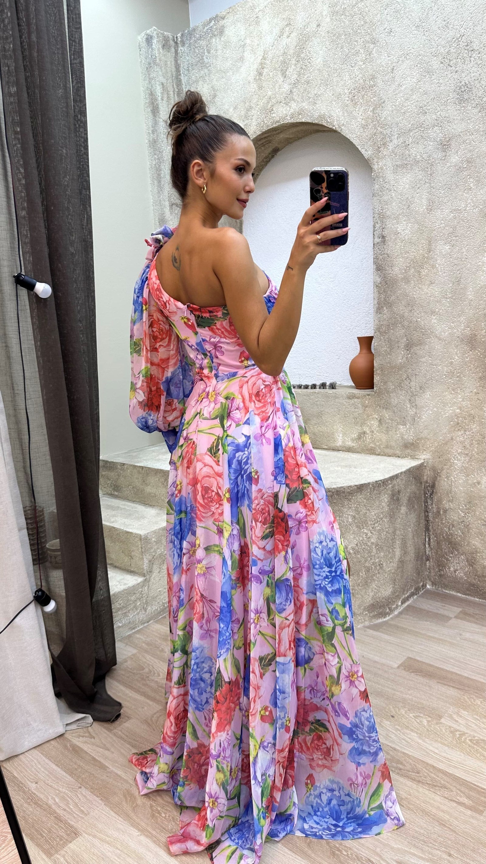 Model wearing floral maxi dress from side angle, showing asymmetric neckline
