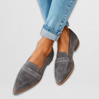Woman wearing suede loafers while sitting, showing comfortable fit and styling