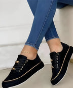 Model wearing white trainers with gold accents, standing pose