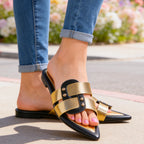 Woman seated wearing white mules, leg detail shot